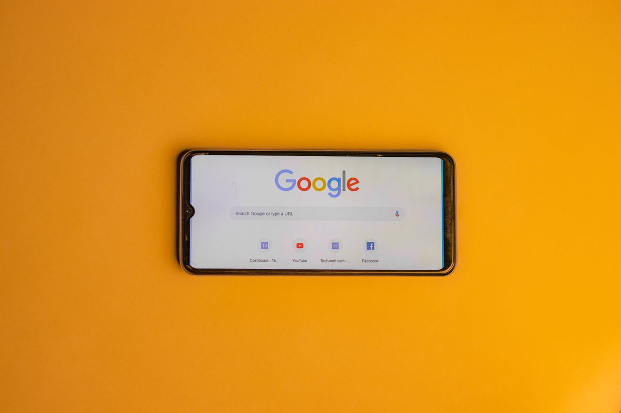 about-01 Smartphone displaying Google search page on a vibrant yellow background.